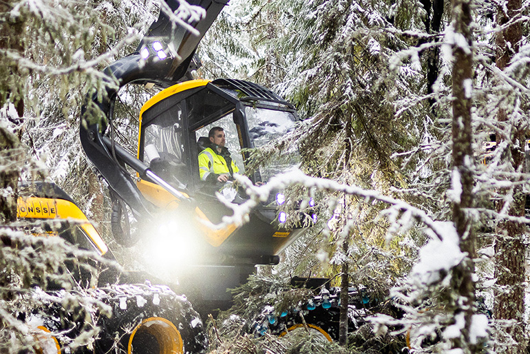 Kuvassa Petri Lahtinen työskentelee metsänhakuukoneen ohjaimissa metsässä.
