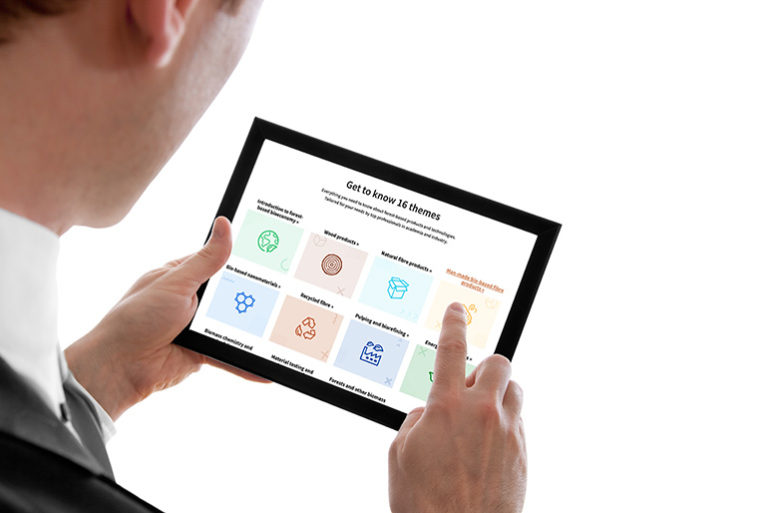Liikemies pitää tablettia käsissään ja koskettaa yhdellä sormellaan näyttöruutua.