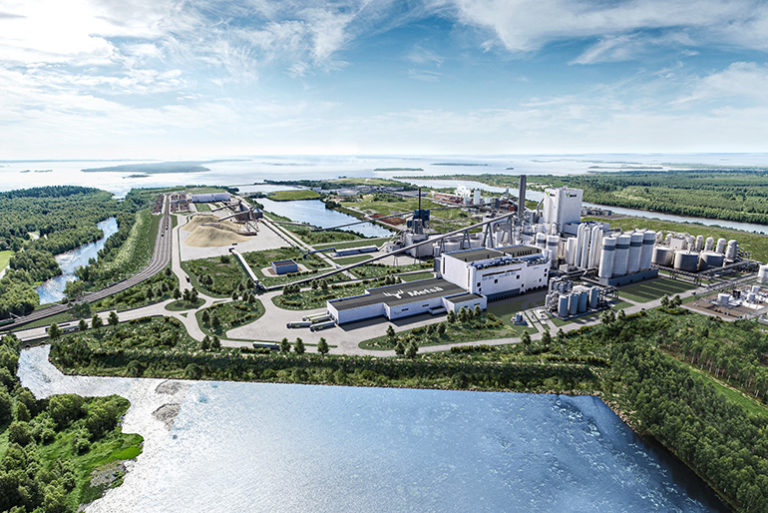 Kesäisen vihreän merimaiseman keskellä puuteollisuuden tuotantolaitoksia.