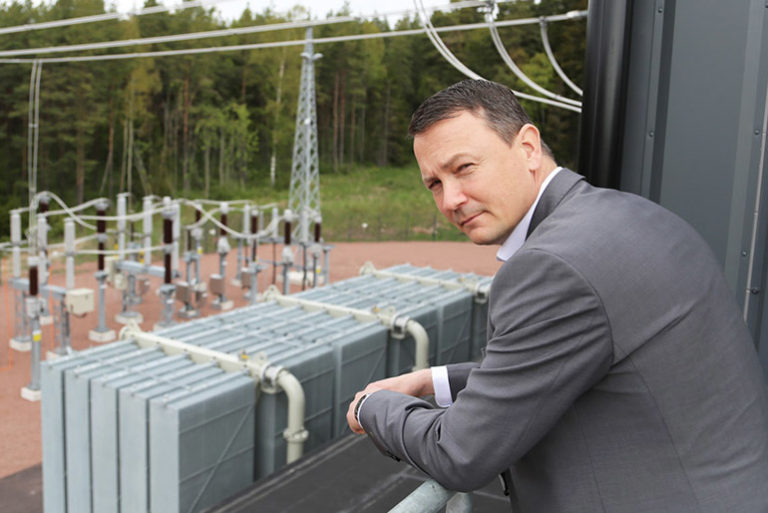 Mieshenkilö seisoo sähkön jakeluaseman edessä