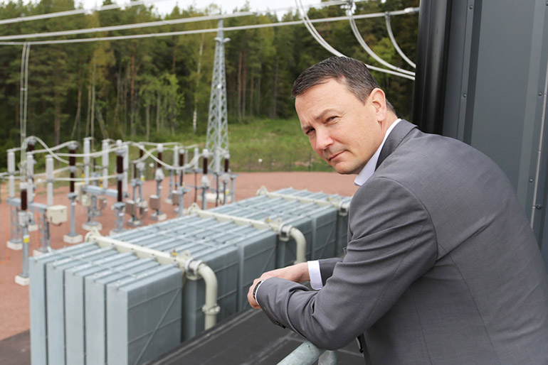 Mieshenkilö seisoo sähkön jakeluaseman edessä