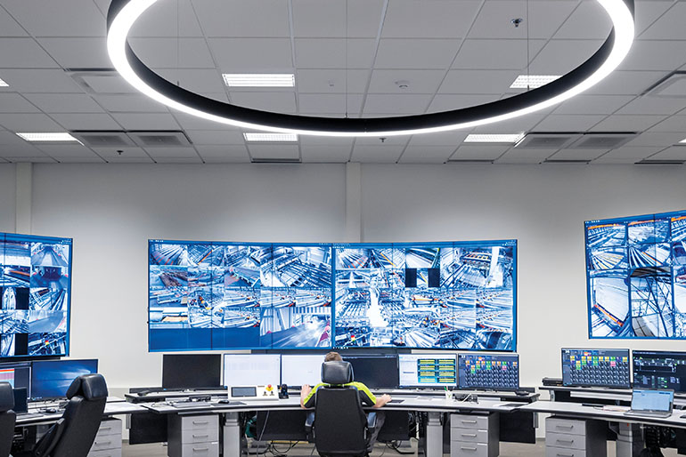 Henkilö työskentelee Rauman sahan ohjauskeskuksessa isojen tv-ruutujen äärellä.