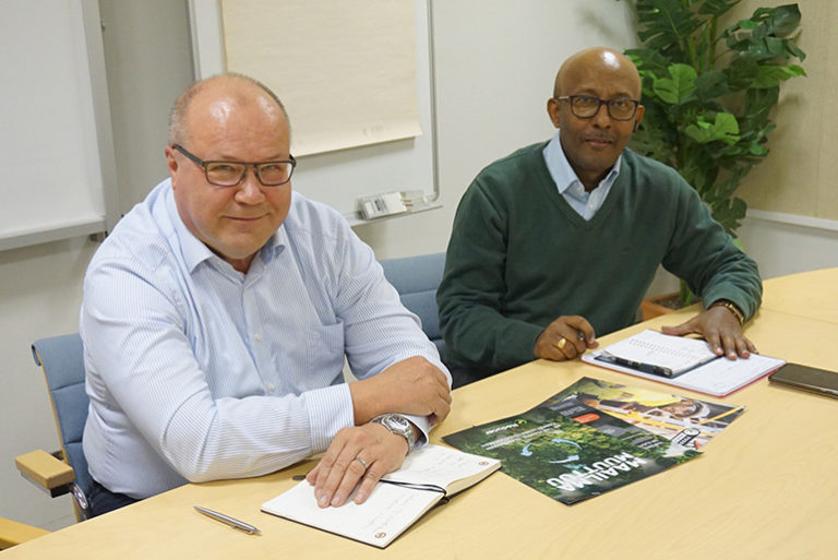 Martti Husu ja Demis Nadew istuvat pöydän ääressä ja katsovat kohti kameraa.