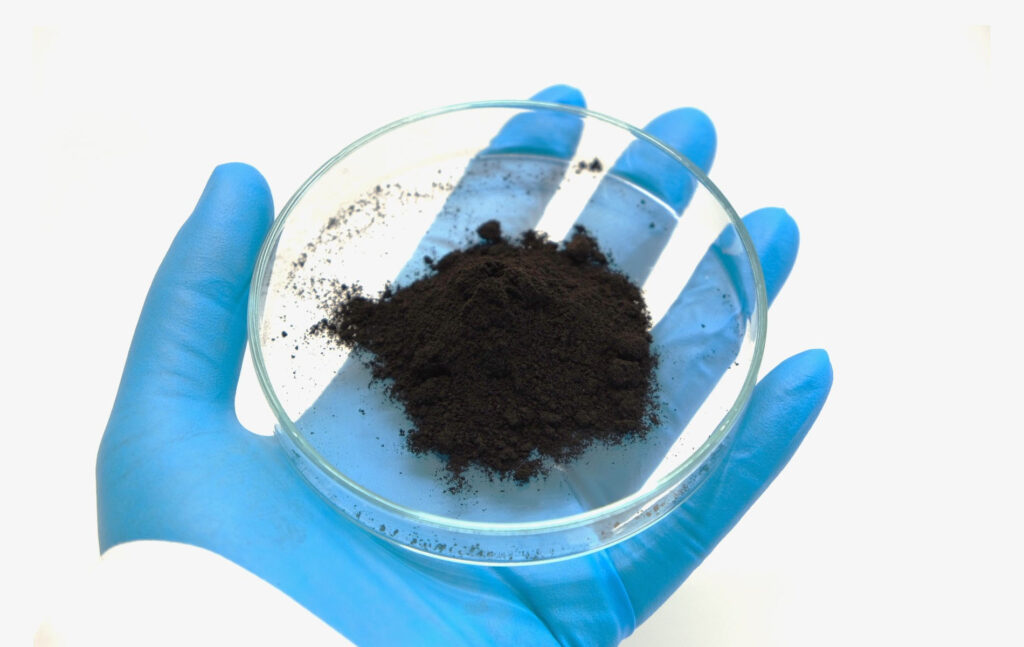 Kähdessä mittalasi, jonka pohjalla on mustaa ligniinimassaa.