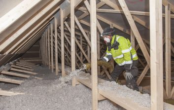 Henkilö puhaltaa rakennuksen yläpohjaan eristeeksi ekovillaa.